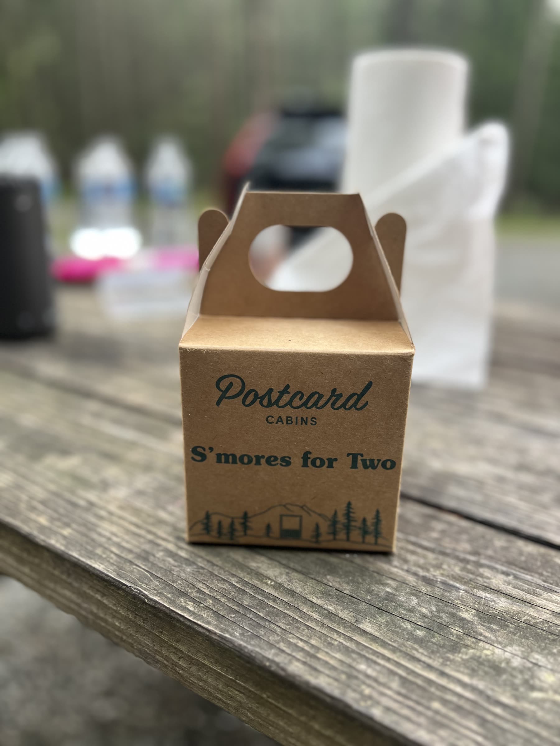 Postcard Cabins s'mores kit for two sitting on a wooden picnic table